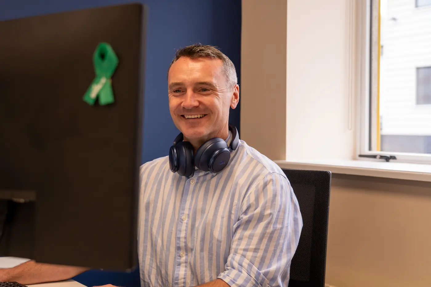 A support engineer smiling at his desk