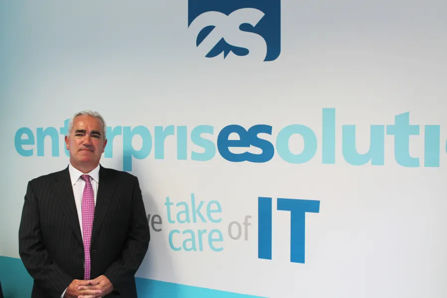A member of the team in front of the Enterprise Solutions logo wall