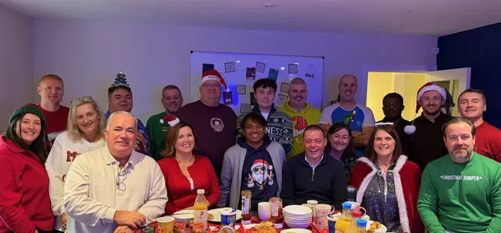 The team in Christmas jumpers around the office table